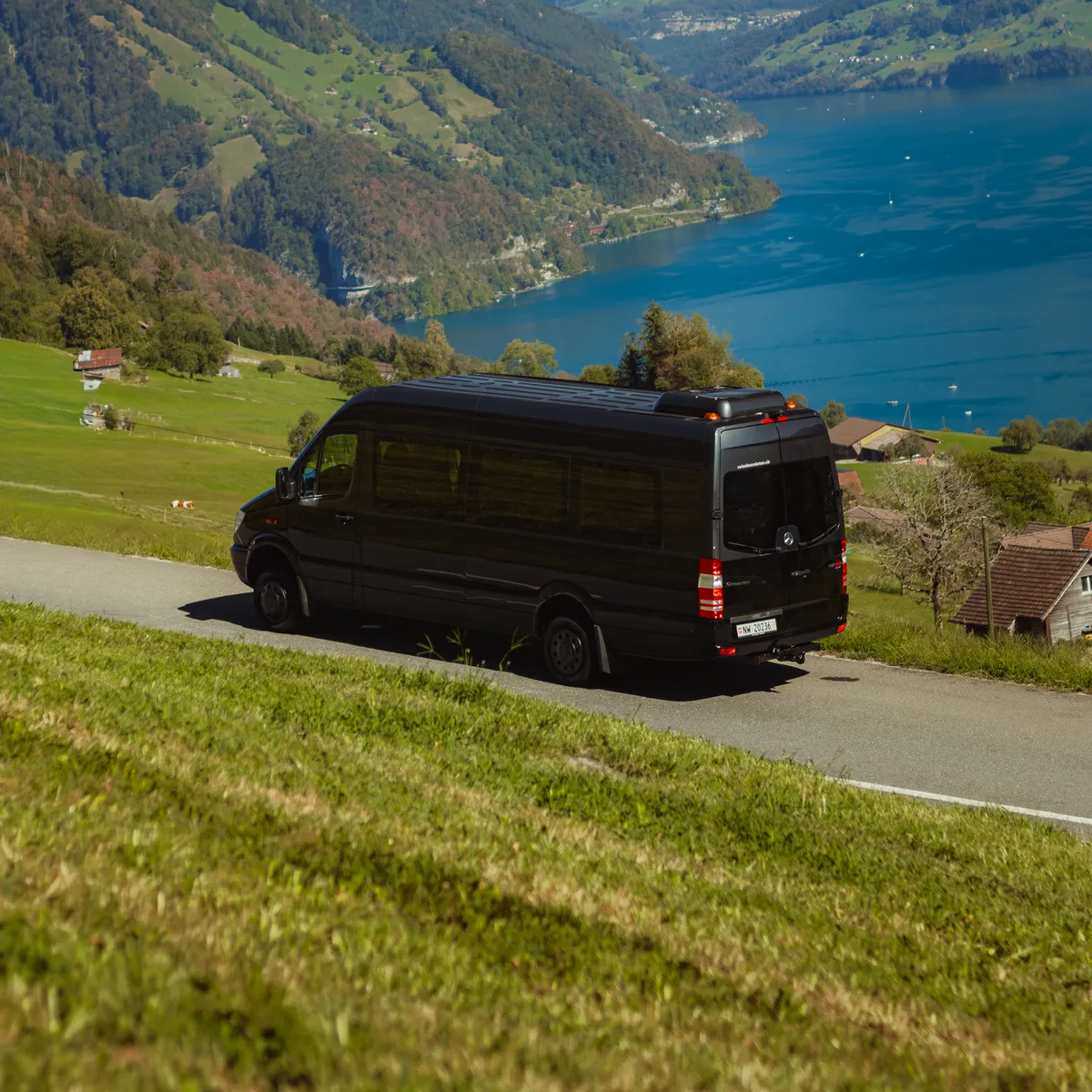 Mercedes-Benz Sprinter auf einer Bergstrasse mit Blick über den See auf die Alpen