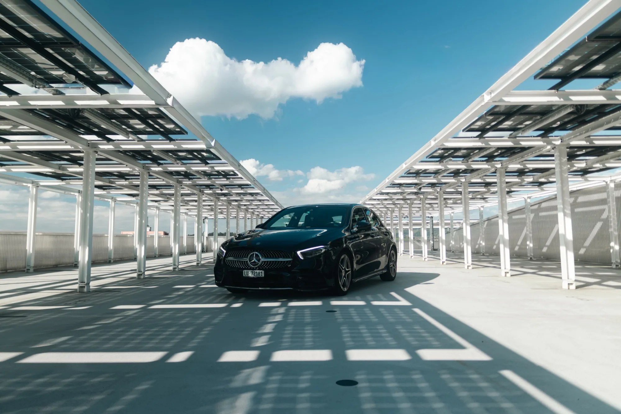 Schwarze Mercedes-Benz A-Klasse schräg von vorne auf einem Parkdeck unter einer Solarüberdachung